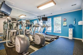 A gym with treadmills and other exercise equipment and a tv